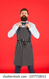 His Style Works Really Well To Compliment Beard. Bearded Man Fixing Bow Tie In Bib Apron. Elegant Hipster With Bearded Face. Bearded Bartender Or Cook In Work Uniform. Long Bearded Waiter Or Servant.