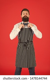 His Style Works Really Well To Compliment Beard. Bearded Man Fixing Bow Tie In Bib Apron. Elegant Hipster With Bearded Face. Bearded Bartender Or Cook In Work Uniform. Long Bearded Waiter Or Servant.