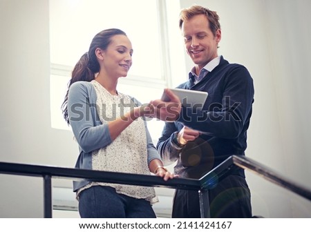 His tablet makes scheduling on the move easier. Shot of two colleagues using a digital tablet while standing in a stairwell.
