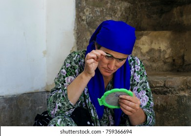 HISOR, TAJIKISTAN – JULY 7, 2013 : Tajik Woman Paint Traditional Unibrow With Homegrown Cosmetic.