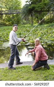 Hispanic 14 Year Old Teen Boy And Father Fishing In Pond