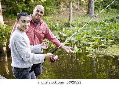 Hispanic 14 Year Old Teen Boy And Father Fishing In Pond