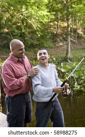 Hispanic 14 Year Old Teen Boy And Father Fishing In Pond