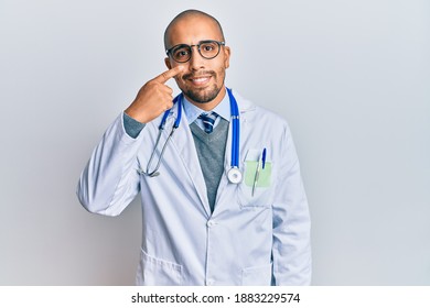 Hispanic Adult Man Wearing Doctor Uniform And Stethoscope Pointing With Hand Finger To Face And Nose, Smiling Cheerful. Beauty Concept 