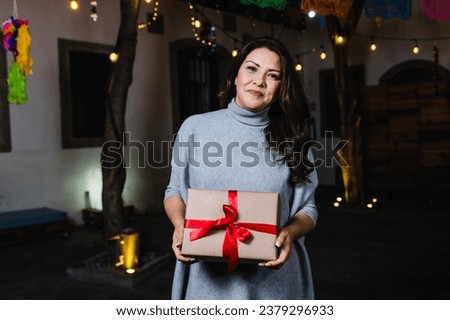 Hispanic adult woman portrait holding a gif box at traditional posada party for Christmas in Mexico Latin America
