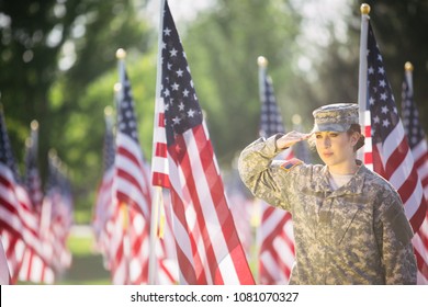 Hispanic American Female Soldier in uniform saluting in front of American flags