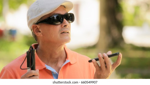 Hispanic blind man with disability. Visually impaired man using Digital Assistant and Ease of Access functions on mobile phone, voice typing to smartphone