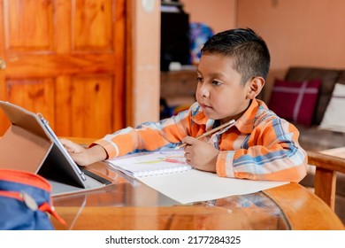 Hispanic boy doing homework at home - Preschool toddler boy drawing - home schooling - kid learning online with tablet - Powered by Shutterstock