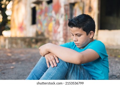 Hispanic Boy Sitting On Some Ruins Looking At The Horizon, With A Sad Expression.