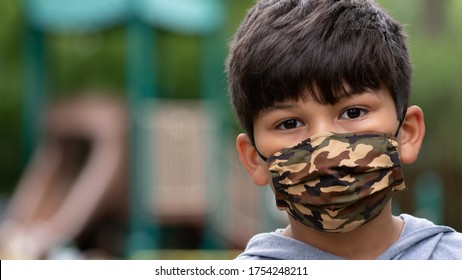Hispanic boy wearing mask with playground in back during coronavirus covid-19 pandemic social distance, stay at home restrictions 