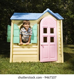 Hispanic Boy In Window Of Outdoor Playhouse Smiling At Viewer.