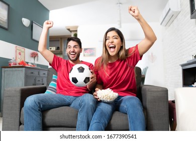 Hispanic Boyfriend And Girlfriend Cheering While Watching Soccer Match At Home