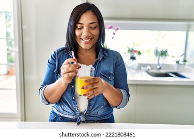 Hispanic Brunette Woman Drinking A Glass Of Fresh Orange Juice At The Kitchen