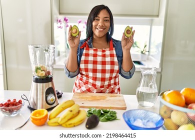 Hispanic Brunette Woman Preparing Fruit Smoothie Holding Avocado At The Kitchen