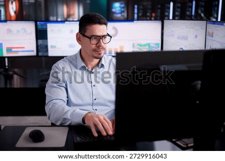 Hispanic Business Analyst Using Multiple Data Dashboards In Office