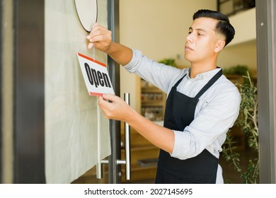 Hispanic Business Owner Putting The Open Sign At The Front Door Of His Sustainable Grocery Store