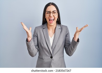 Hispanic business woman wearing glasses celebrating crazy and amazed for success with arms raised and open eyes screaming excited. winner concept  - Shutterstock ID 2183567267