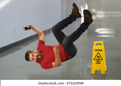 Hispanic businessman falling on wet floor inside building