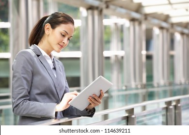 Hispanic Businesswoman Working On Tablet Computer Outside Office