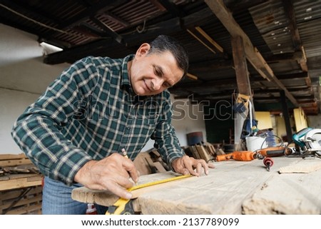Hispanic carpenter working in his workshop - man working with carpentry tools - happy carpenter working
