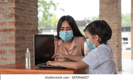 Hispanic Child Taking Online Class On Computer Laptop, His Brunette Mother Accompanies Him