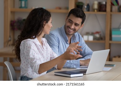 Hispanic colleagues sit at desk with laptop discuss corporate software. Mentor provide help to workmate, consider collaborative task. Sales manager and client business meeting in office, tech concept