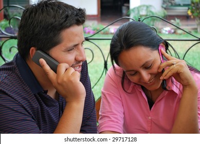 A Hispanic Couple.  Both Are Talking On The Phone.