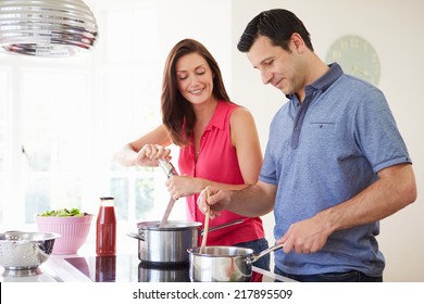 Hispanic Couple Cooking Meal At Home Together