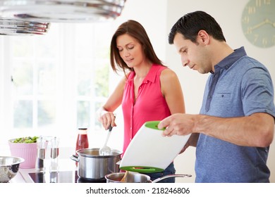 Hispanic Couple Cooking Meal At Home Together