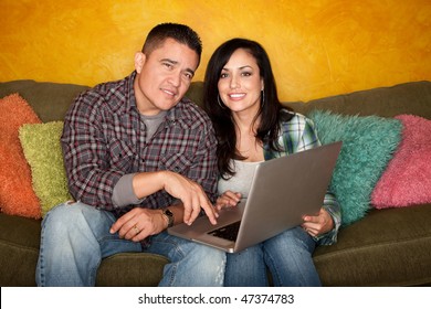 Hispanic Couple On Green Couch With Computer