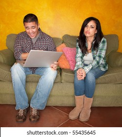 Hispanic Couple On Green Couch With Computer Woman Is Bored