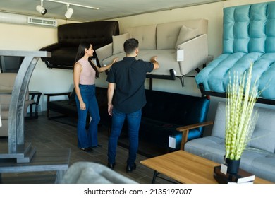 Hispanic Couple Seen From Behind Looking To Buy A Beautiful Couch Together At The Furniture Store