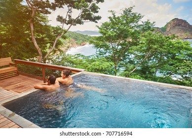 Hispanic Couple Staying In Spa Pool On Sunny Nature Background