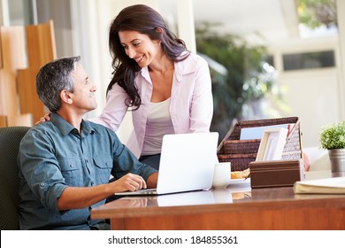 Hispanic Couple Using Laptop On Desk At Home