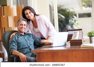 Hispanic Couple Using Laptop On Desk At Home