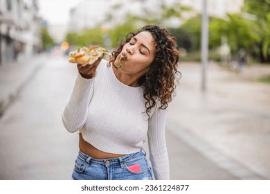 A Hispanic curvy woman indulges in a slice of pizza on the bustling street, savoring the flavors of both her culture and her cravings