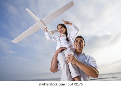 Hispanic Dad And 9 Year Old Child Playing At Beach With Model Plane