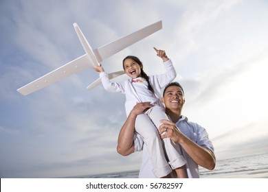 Hispanic Dad And 9 Year Old Child Playing At Beach With Model Plane