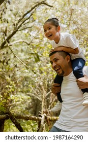 Hispanic Dad Carrying His Daughter On His Shoulders-Family Walking In The Park-Father Playing With His Daughter In The Park