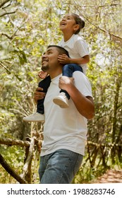 Hispanic Dad Carrying His Daughter On His Shoulders-Family Walking In The Park-Father Playing With His Daughter In The Park