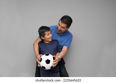 Hispanic dad and son share their love for soccer, they take a ball with their hands excited to watch the football game - Shutterstock ID 2225645633