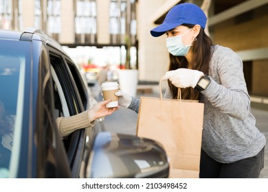 Hispanic Delivery Courier Wearing A Face Mask And Protective Gloves While Giving The Food Order To A Customer In The Car