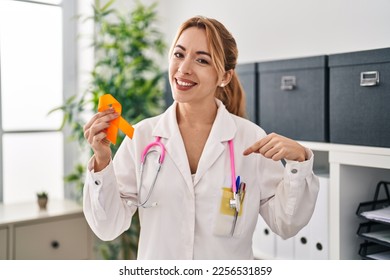 Hispanic doctor woman holding awareness orange ribbon pointing finger to one self smiling happy and proud  - Shutterstock ID 2256531859