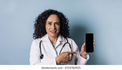 Hispanic Doctor Woman Portrait With Copy Space And Holding A Mobile Phone Over Blue Background Laughing In Mexico Latin America