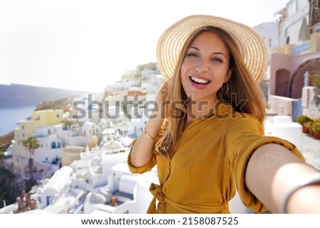 Hispanic exuberant fashion woman having fun taking self portrait on sunset in Santorini Island, Greece