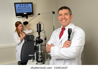 Hispanic Eye Doctor And Female Assistant In Examination Room