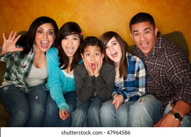 Hispanic Family With Big Facial Reactions Sitting On Couch