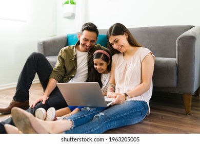 Hispanic Family Calling By Video Call Their Friends. Happy Mom, Dad And Daughter Talking With Their Loving Family During An Online Video Chat In A Laptop