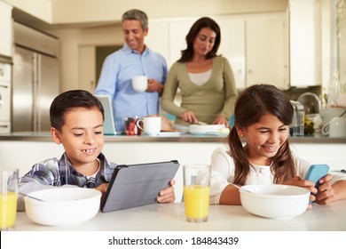 Hispanic Family Eating Breakfast Using Digital Devices