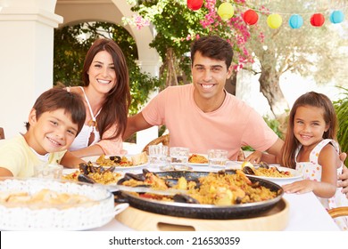 Hispanic Family Enjoying Outdoor Meal At Home Together